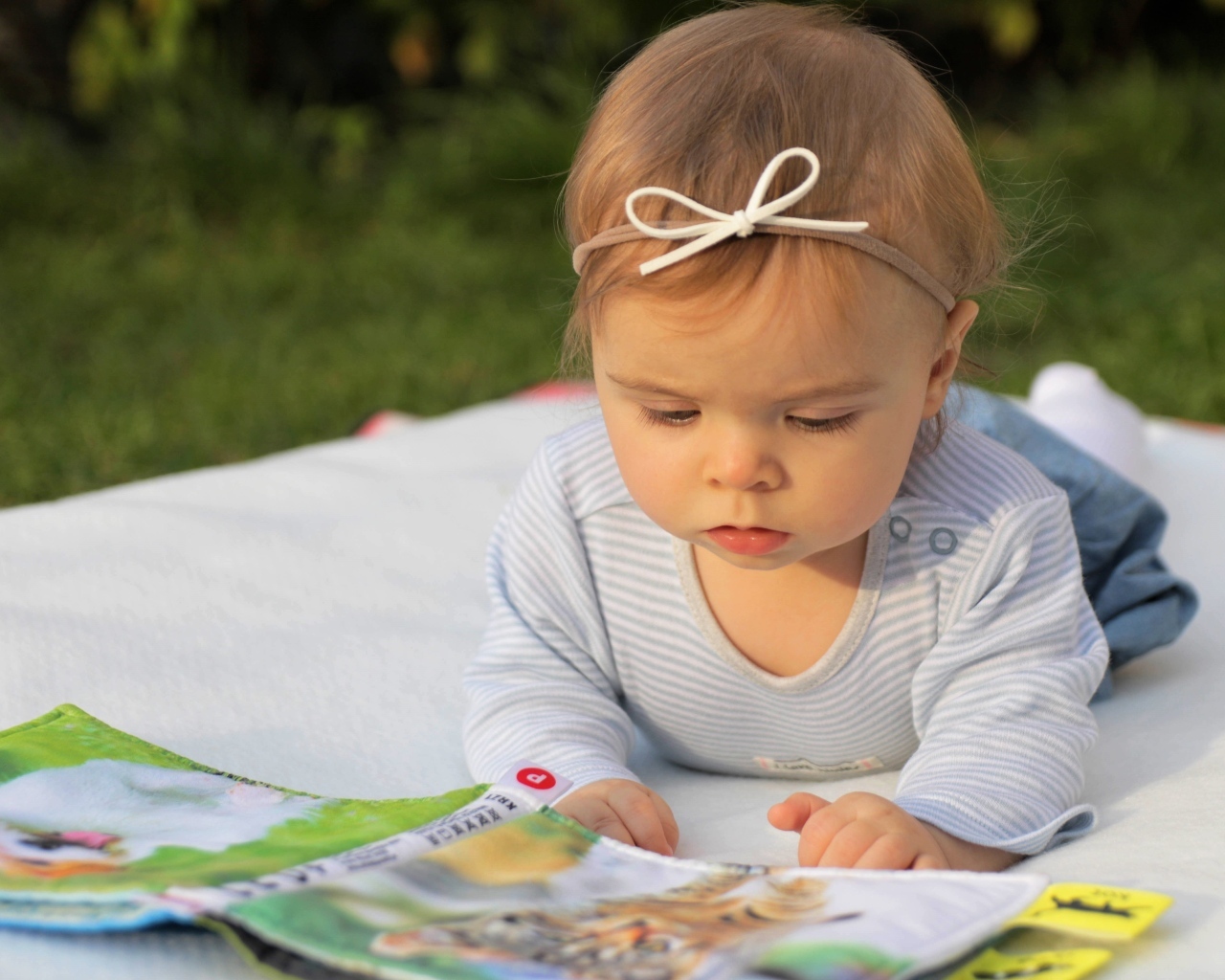 Маленькая девочка с книгой на белом покрывале