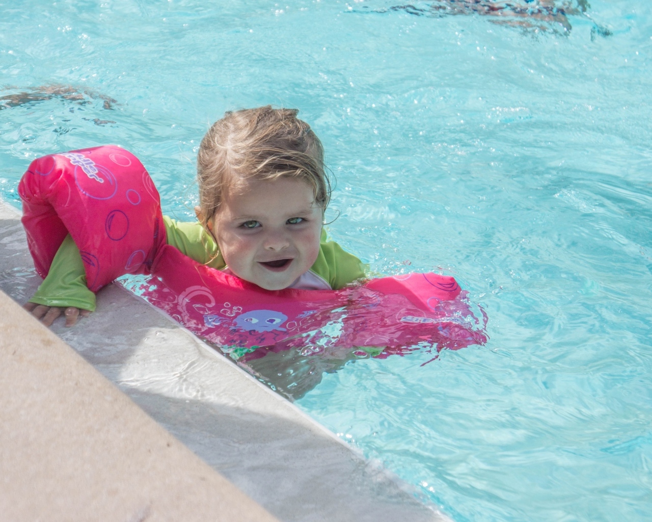 Маленькая девочка со спасательным кругом в бассейне