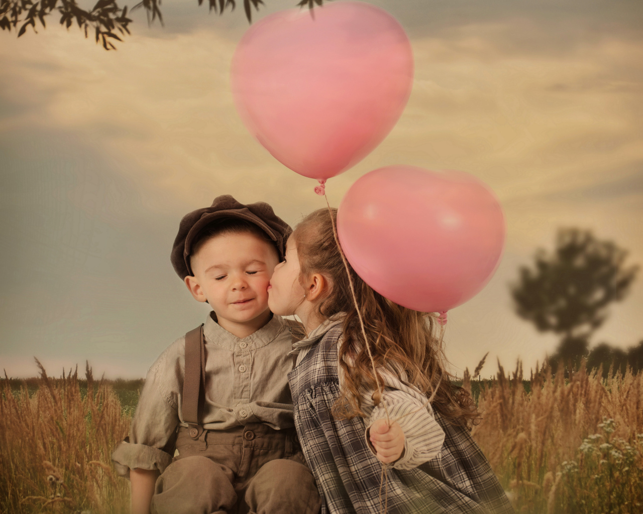 Маленькая девочка с шариками целует мальчика