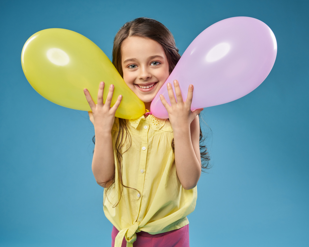 Маленькая девочка с воздушными шариками на голубом фоне