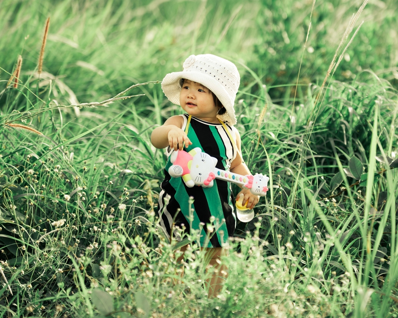 Маленькая девочка с игрушечной гитарой в траве