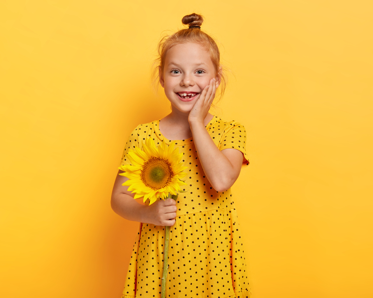 Маленькая рыжеволосая девочка с подсолнухом в руках