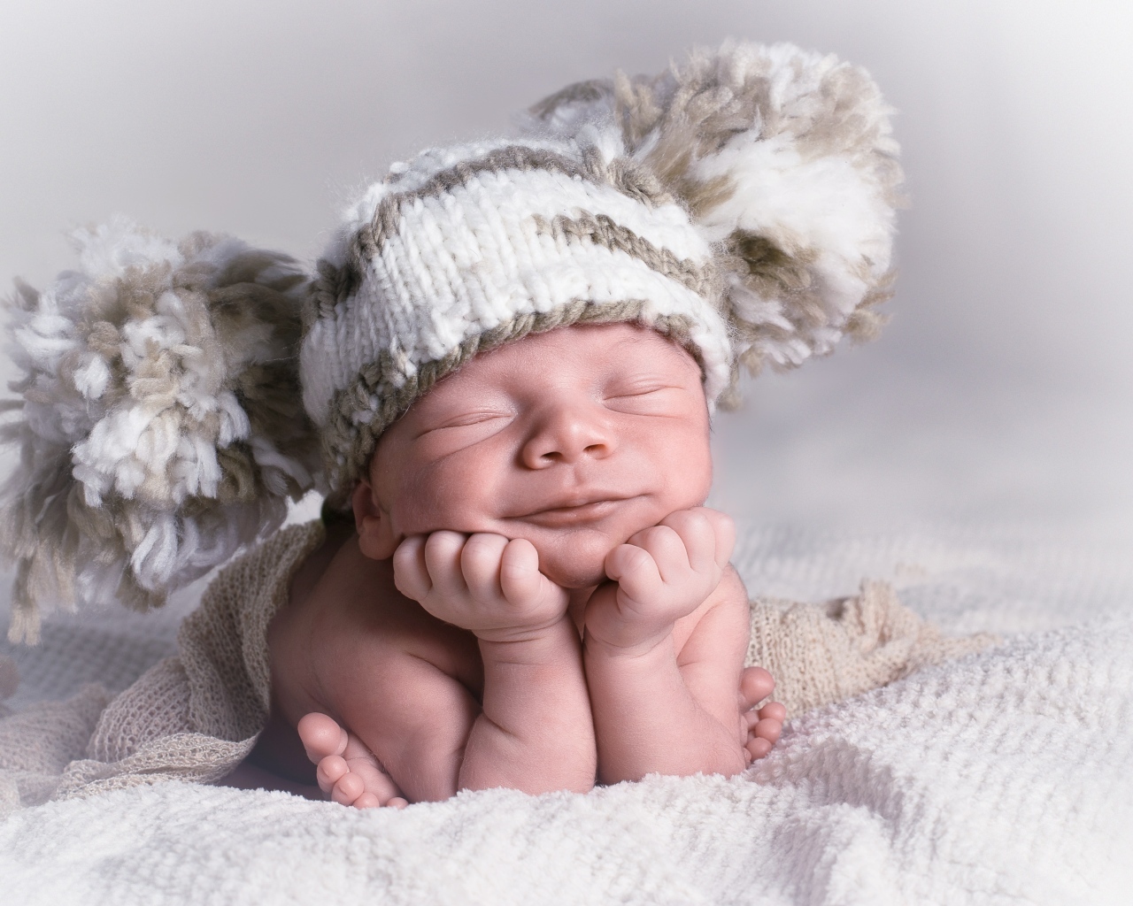 Новорожденный младенец в большой вязаной шапке