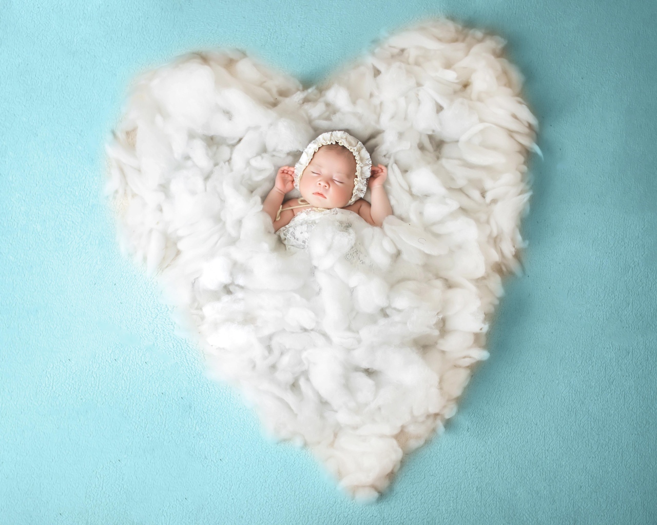 Новорожденный ребенок спит на белом мягком сердце на голубом фоне