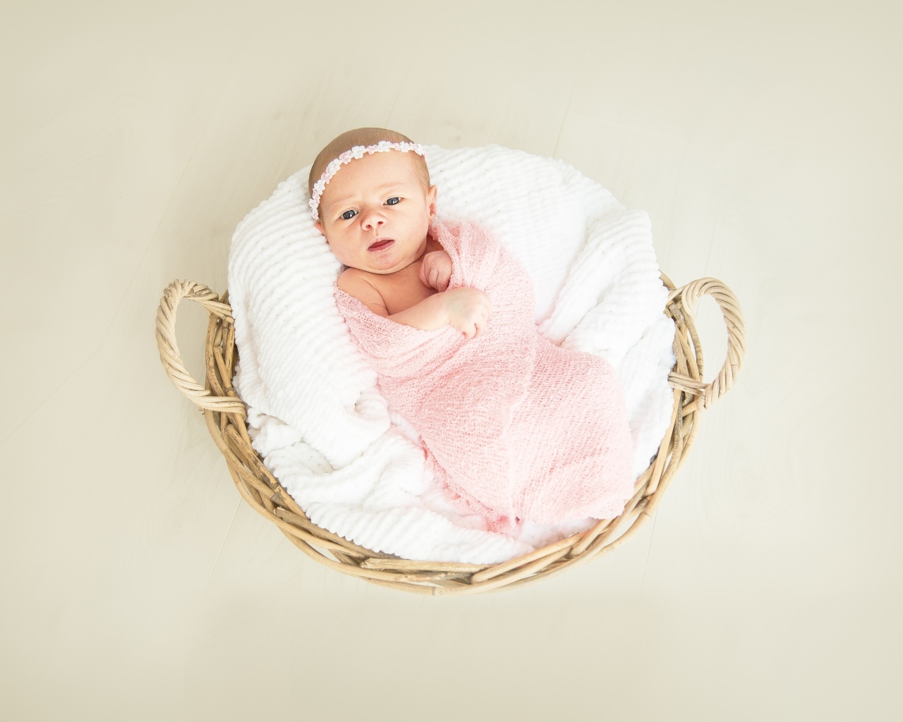 Новорожденная девочка в розовом покрывале в корзине