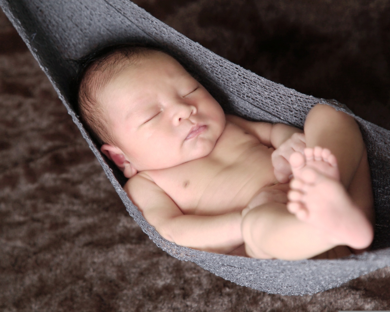 Новорожденный спящий малыш в вязаном гамаке