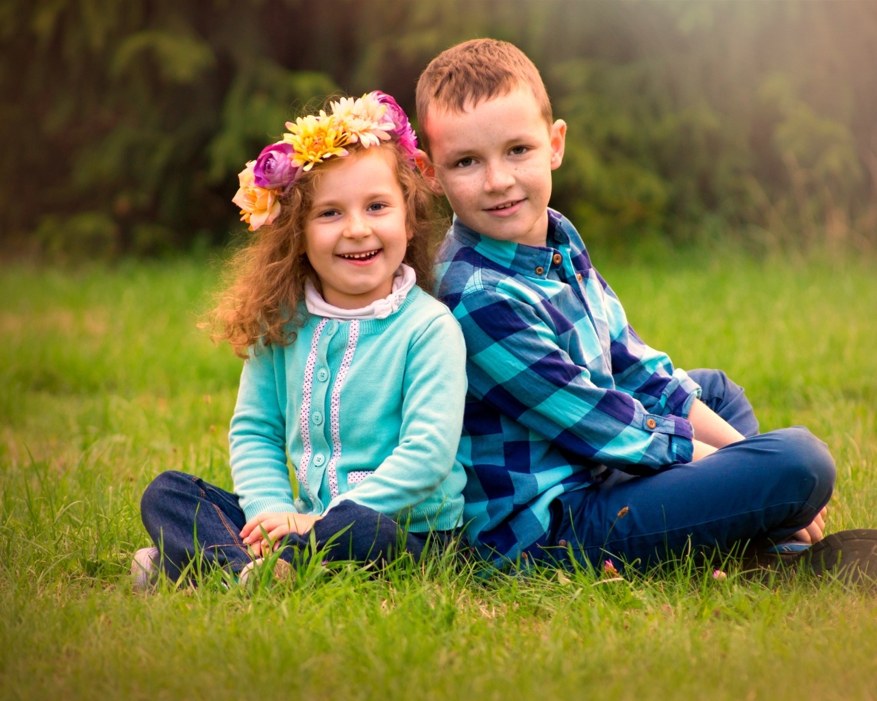 Рыжеволосые мальчик и девочка сидят на траве