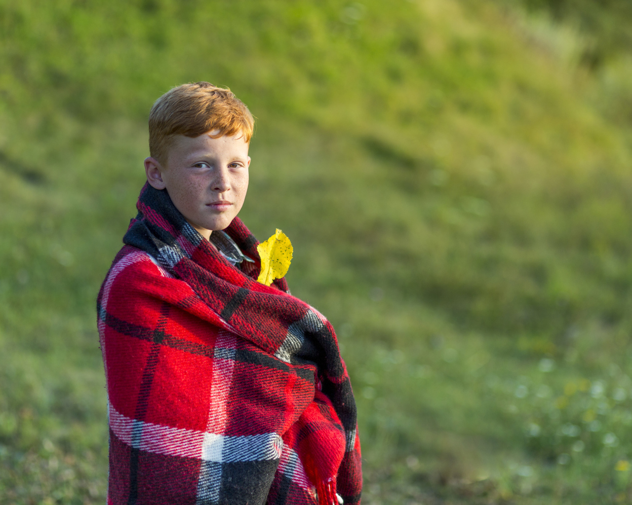 Рыжеволосый мальчик укутан пледом осенью 