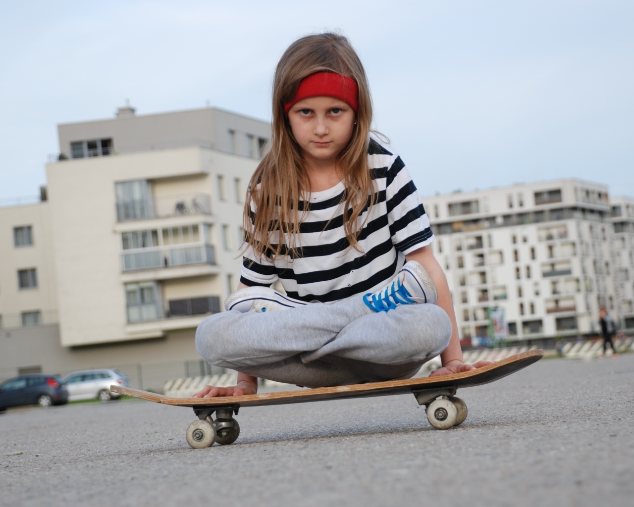 Серьезная девочка сидит на  скейтборде