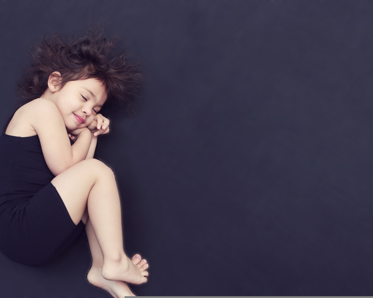 Спящая маленькая девочка на сером фоне
