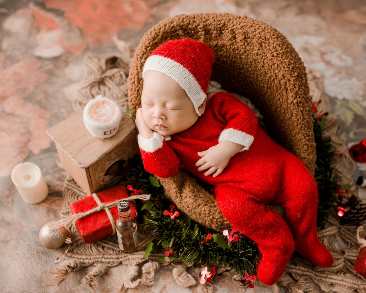 Спящий новорожденный ребенок в красном новогоднем костюме