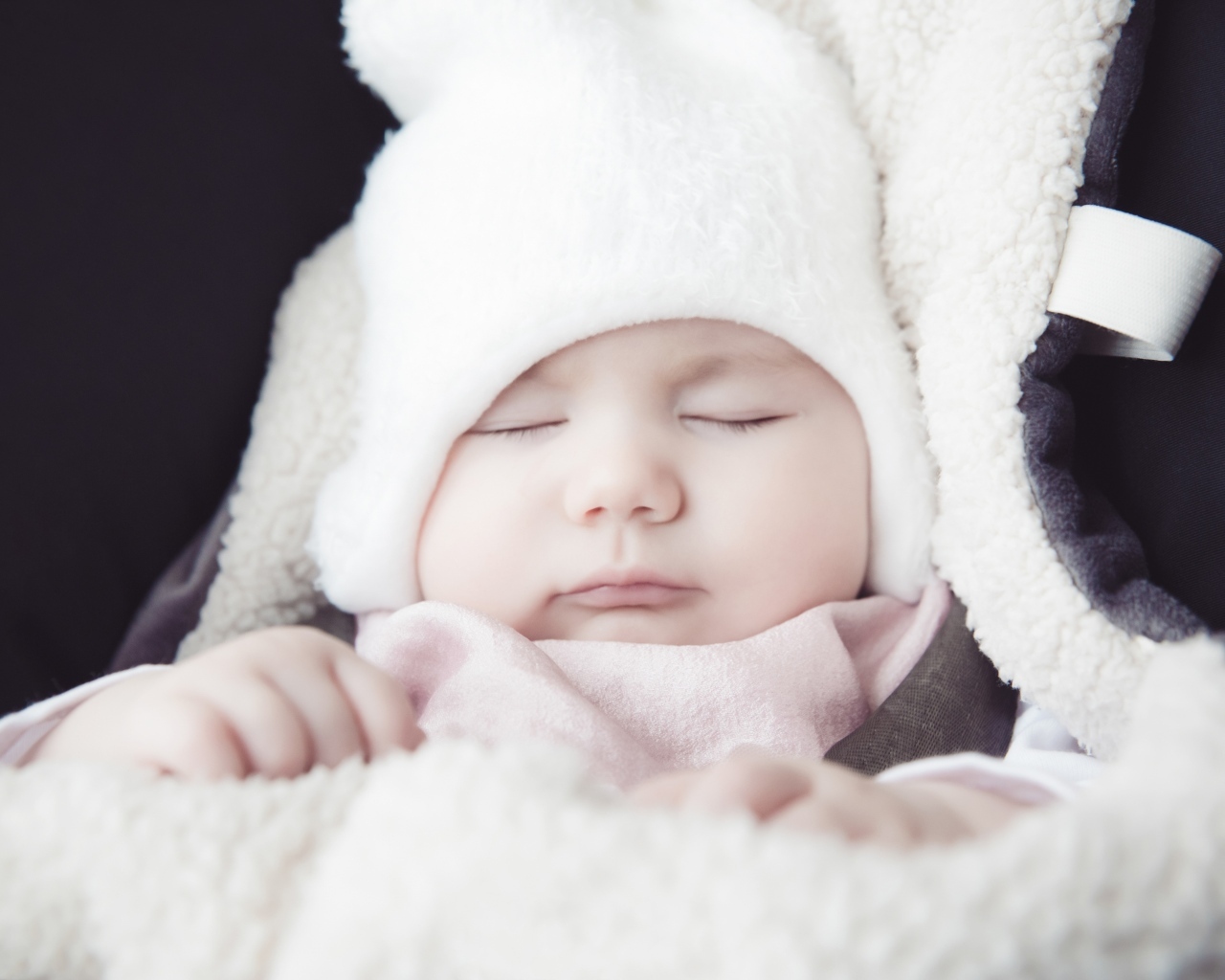 Спящий новорожденный ребенок в белой шапке