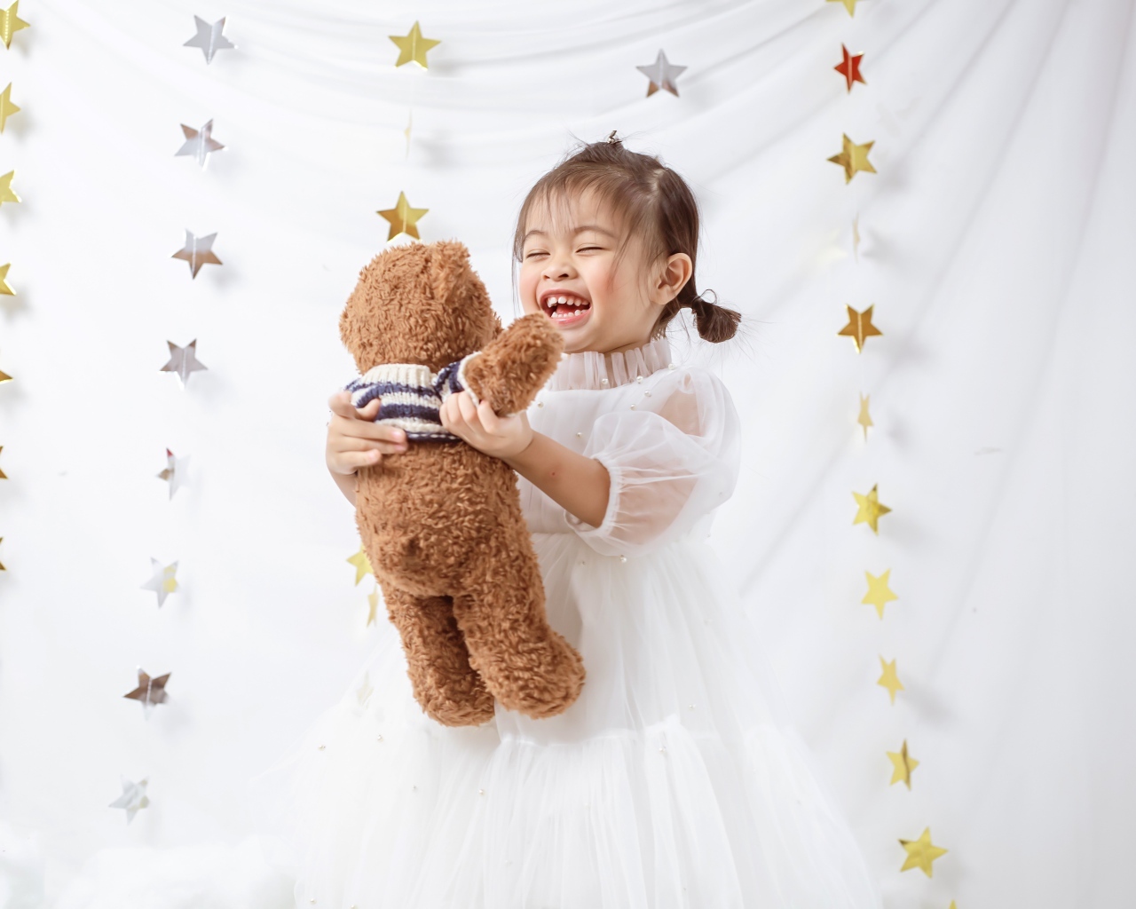 Улыбающаяся девочка азиатка с игрушечным медведем