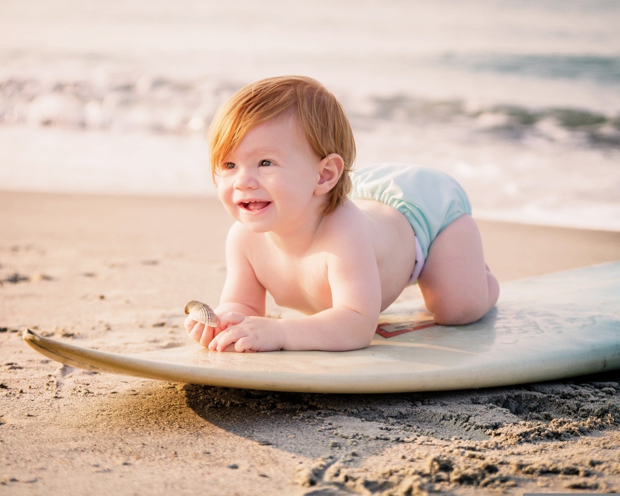 Улыбающийся ребенок с доской для серфинга на пляже