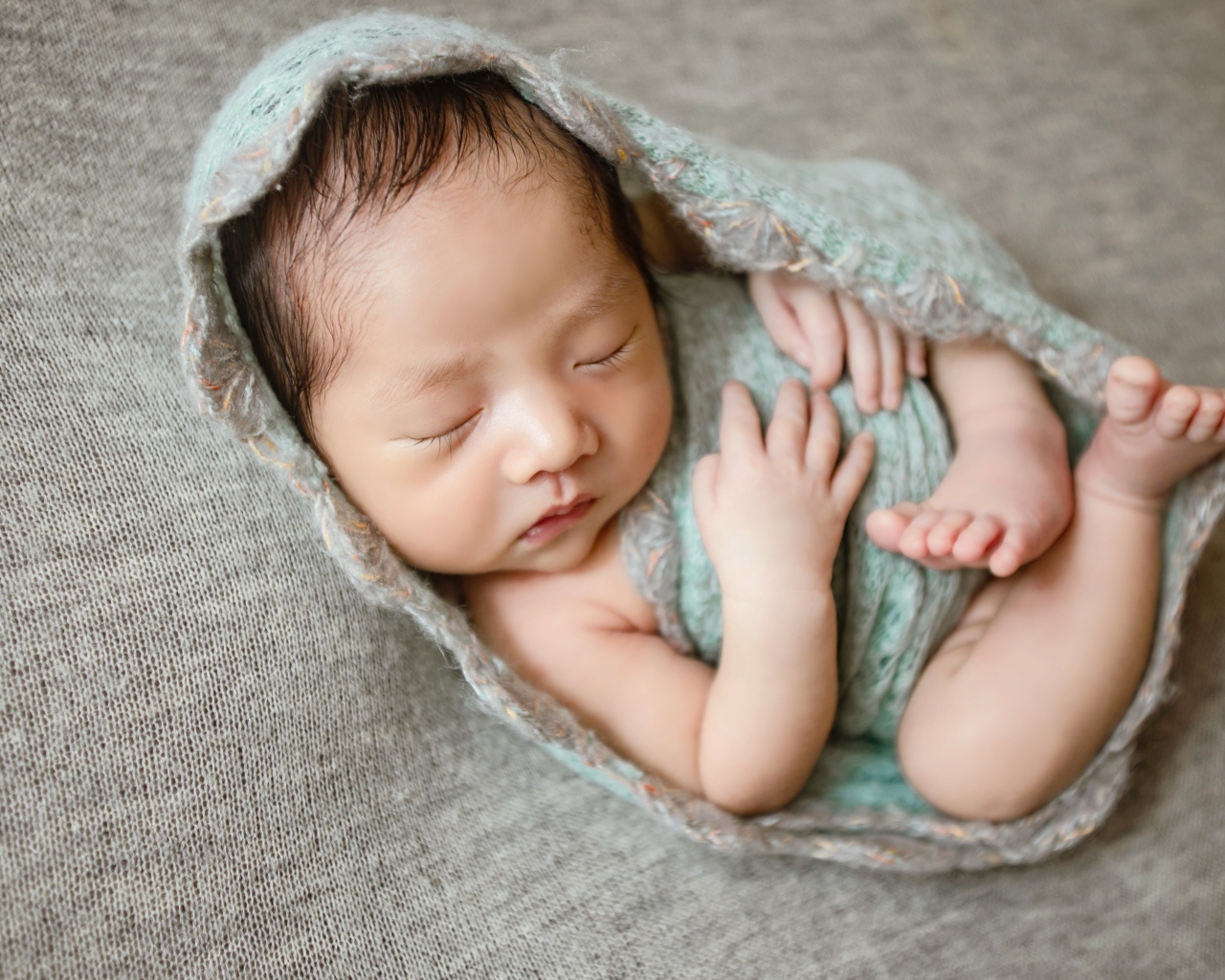 Крошечный новорожденный малыш на сером фоне