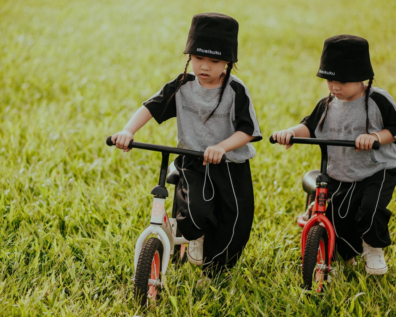 Две девочки с велосипедами на зеленой траве