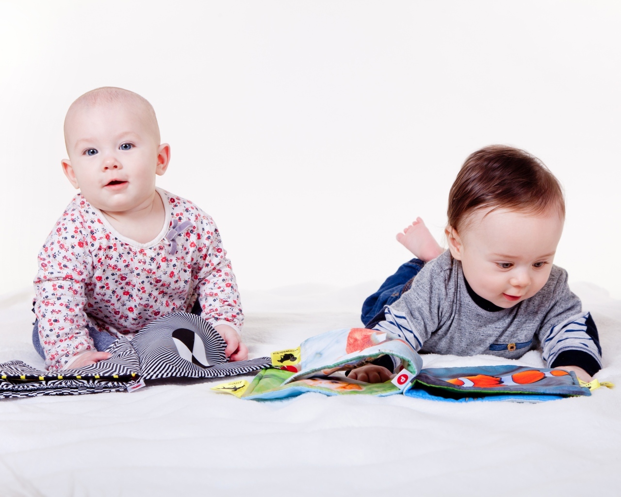 Два маленьких ребенка на кровати с мягкими книгами