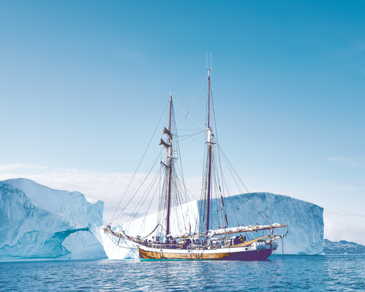 Большой корабль подплывает к голубому айсбергу в море