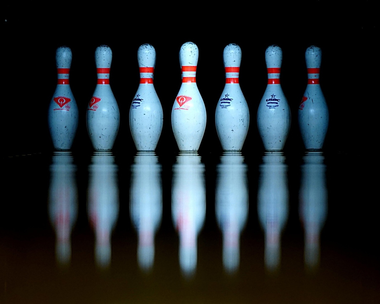 Кегли для боулинга отражаются в черной поверхности 