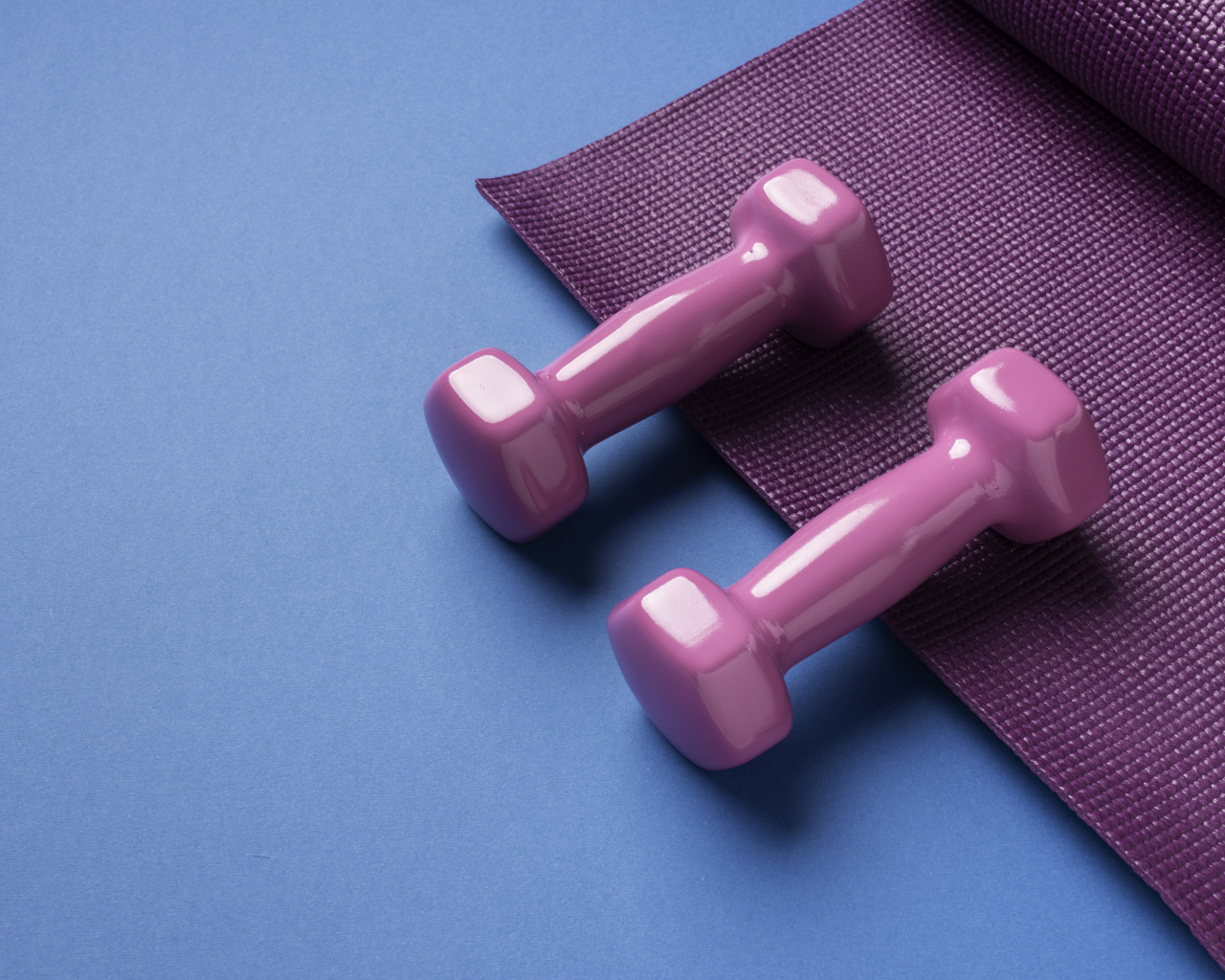 Розовые гантели и коврик на голубом фоне