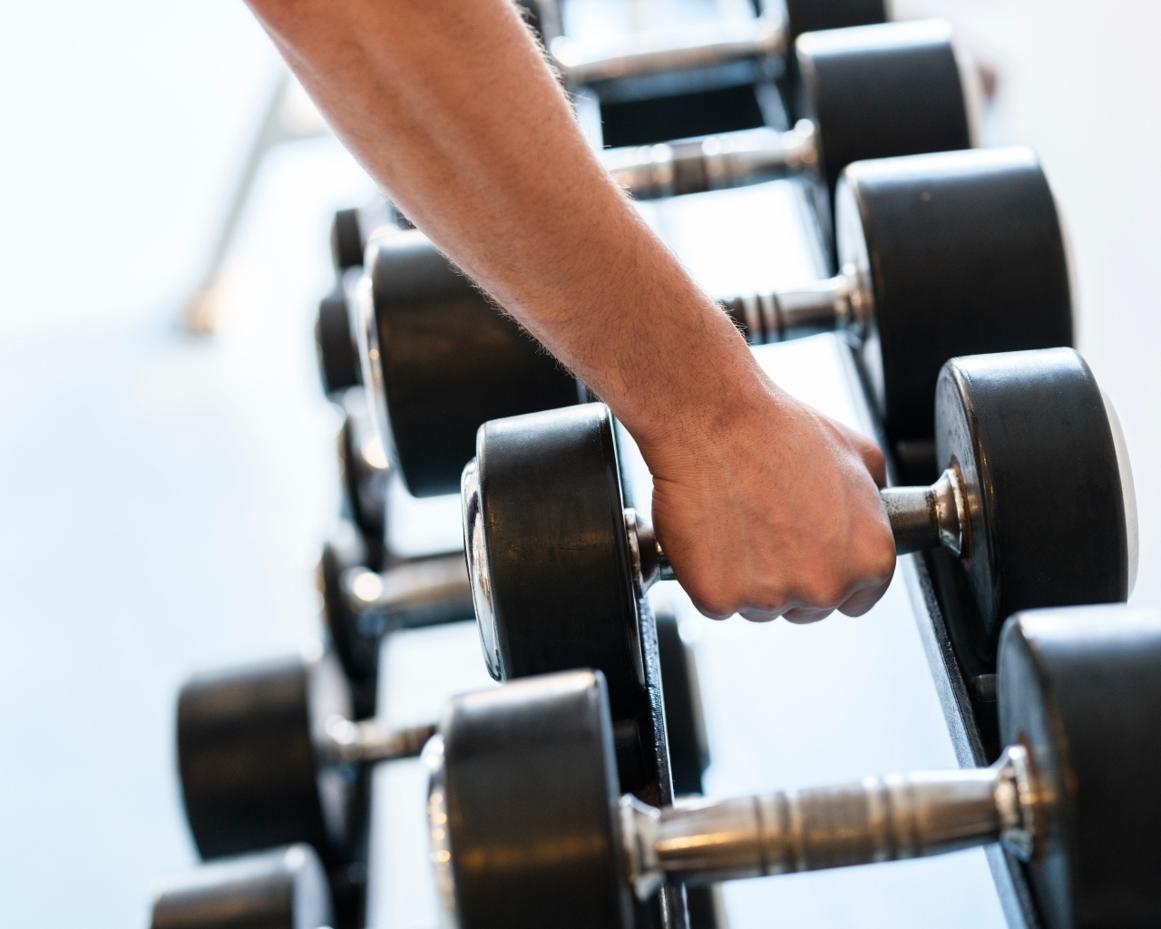 Сильная рука спортсмена берет гантели