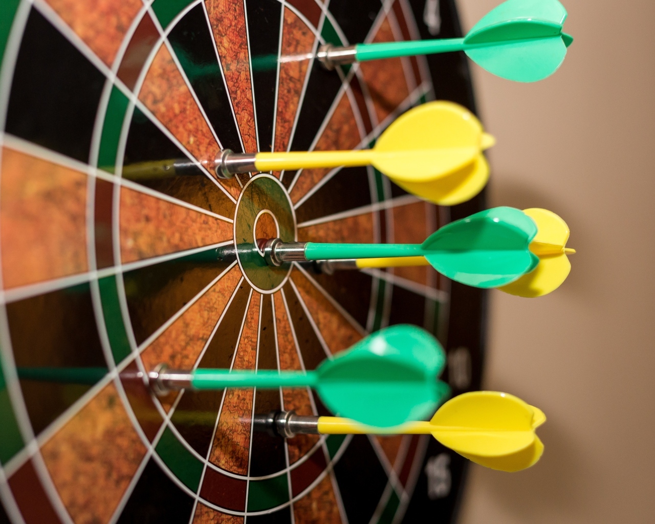 Желтые и зеленые дротики в мишени 