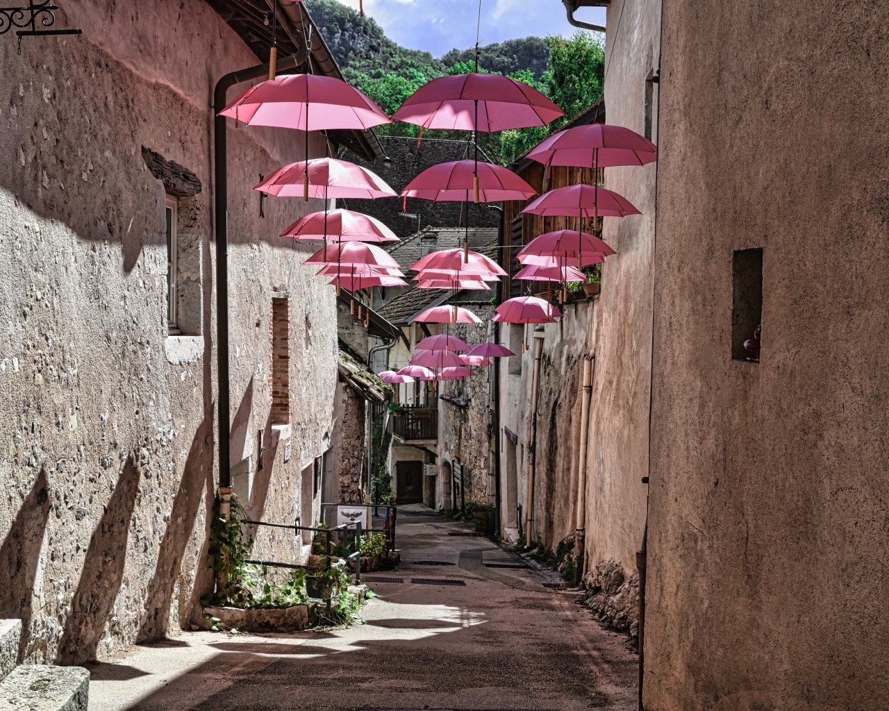 Розовые зонтики украшают узкую улицу