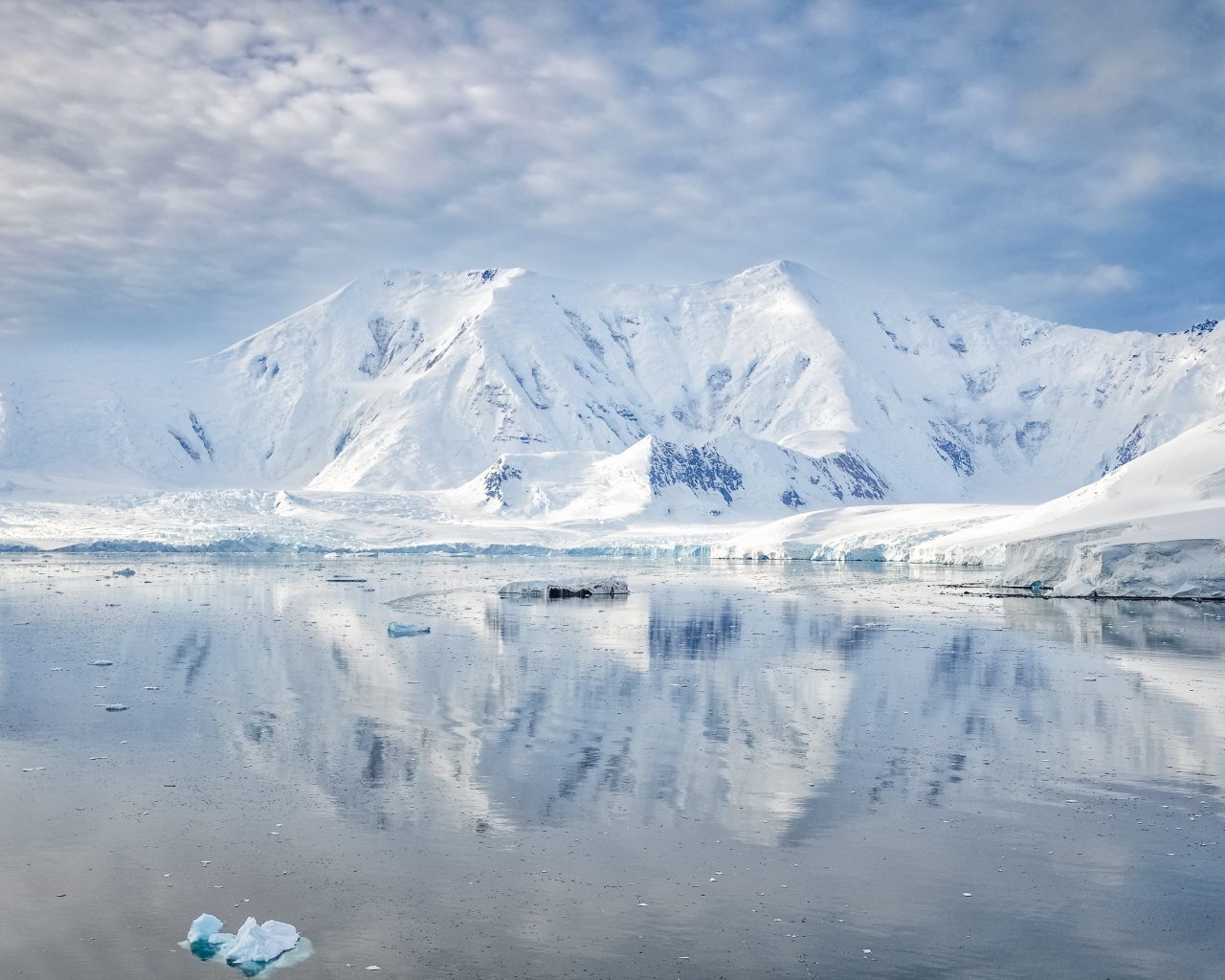 Заснеженные горы под белыми облаками у океана, Антарктида 