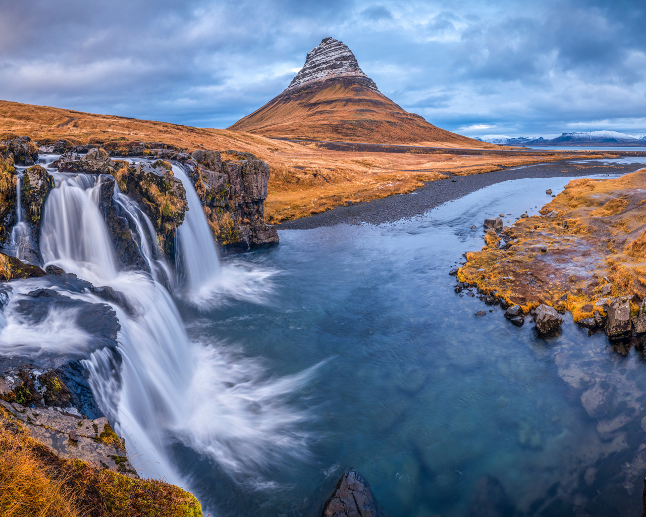 Вид на реку, водопад и гору Киркьюфетль под пасмурным небом Исладнии