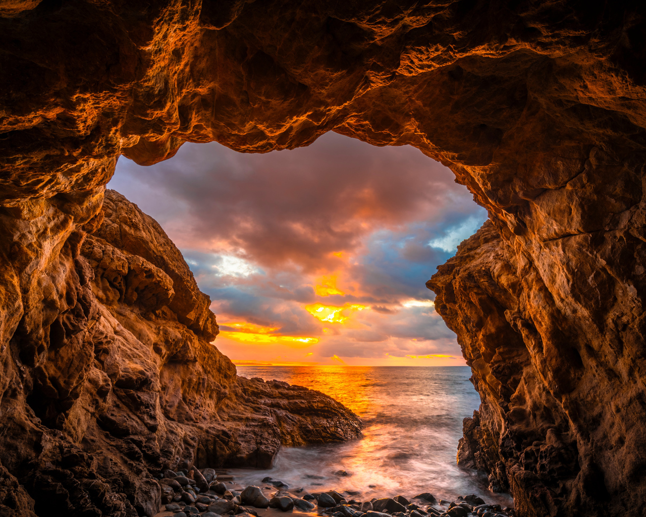 Арка в горе на закате солнца на пляже Малибу, США