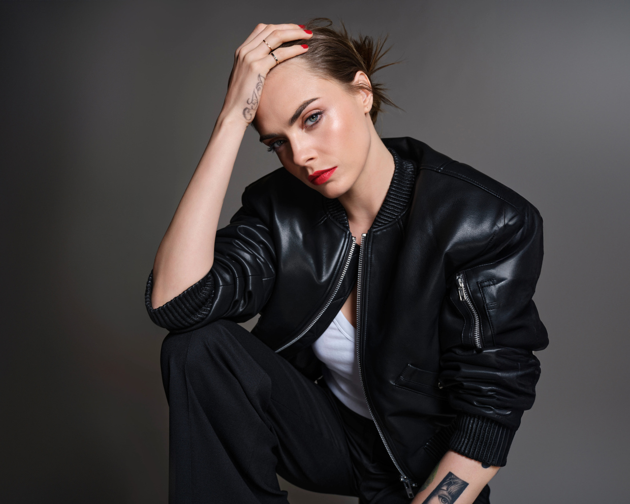 Актриса Кара Делевинь в черной кожаной куртке на сером фоне