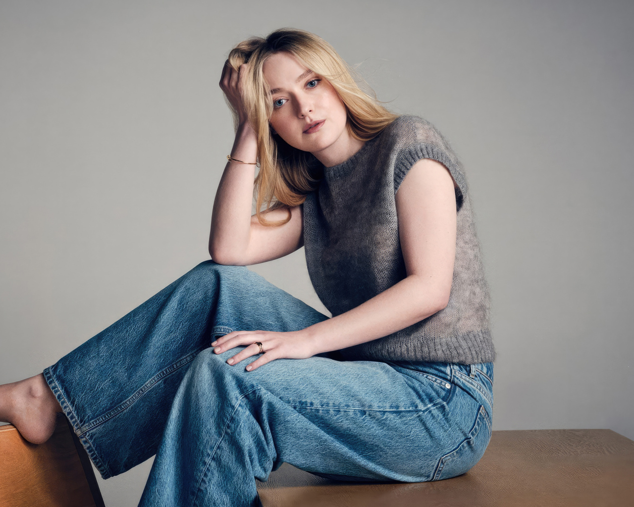Актриса Дакота Фэннинг в джинсах сидит на столе