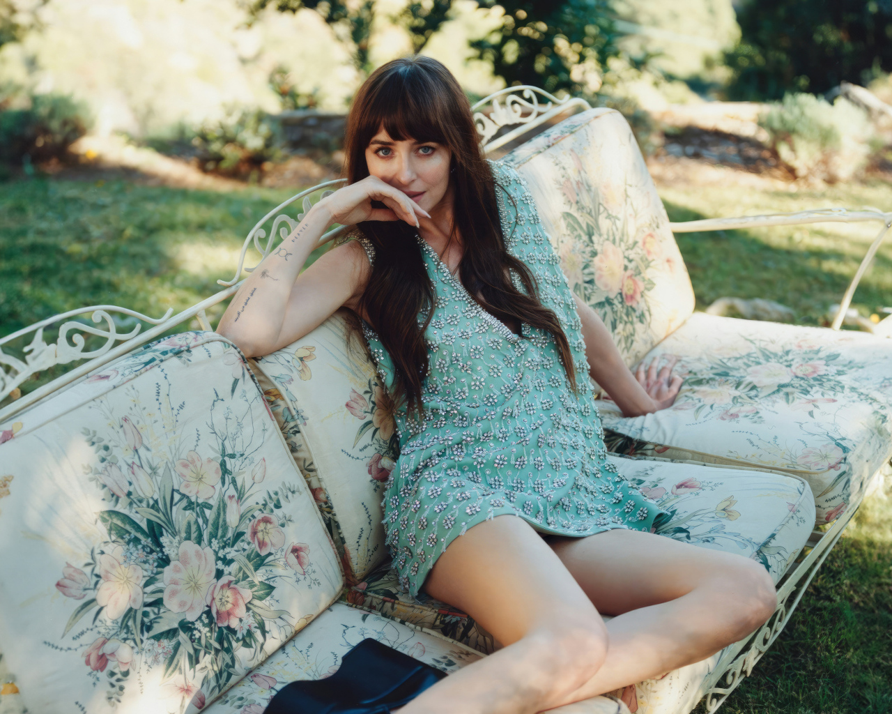 Актриса Дакота Джонсон в платье сидит на диване