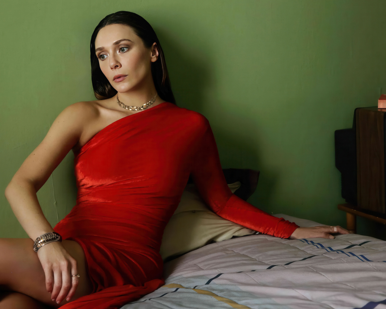 Актриса Элизабет Олсен в красном платье сидит на кровати