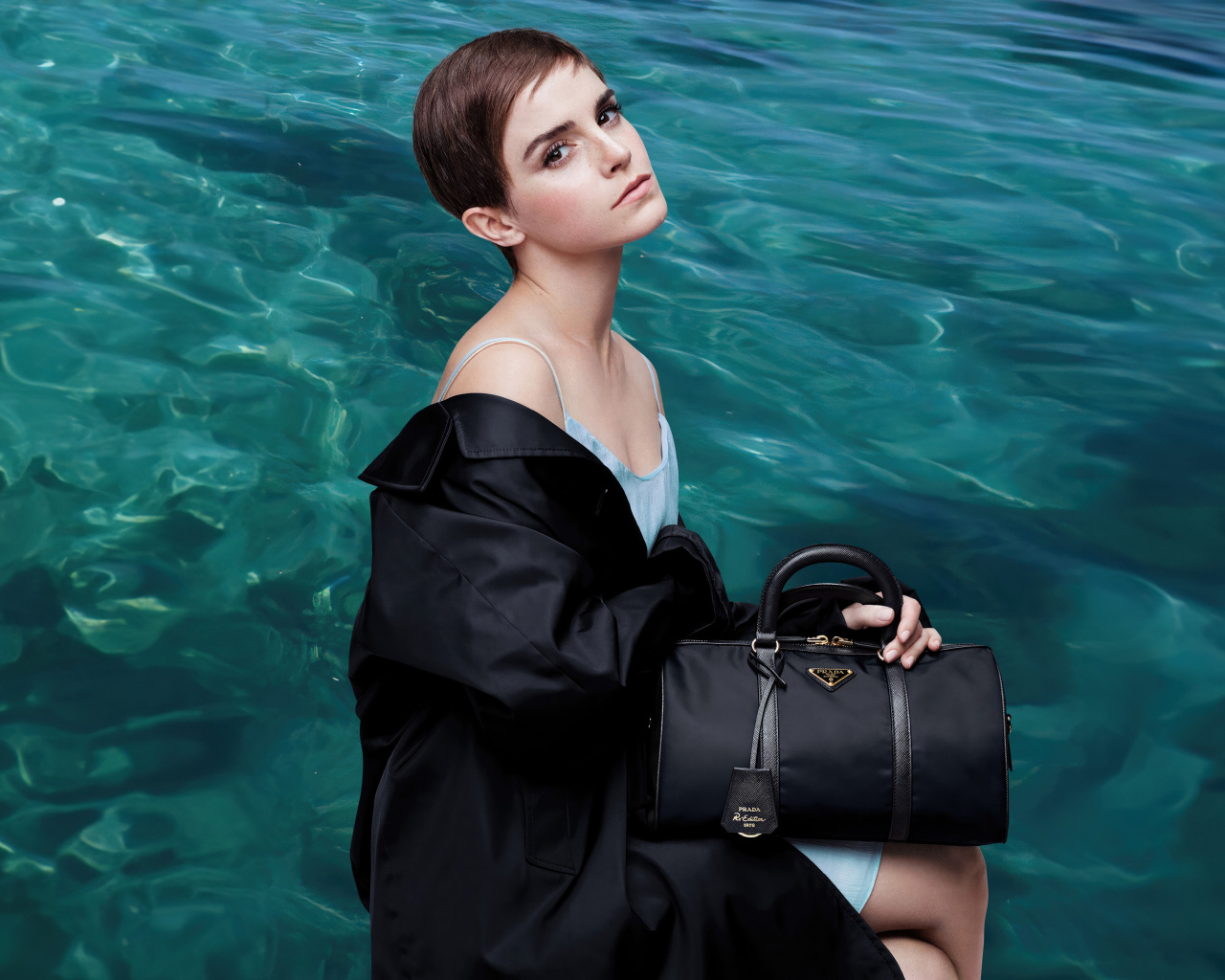 Актриса Эмма Уотсон с сумочкой сидит у воды
