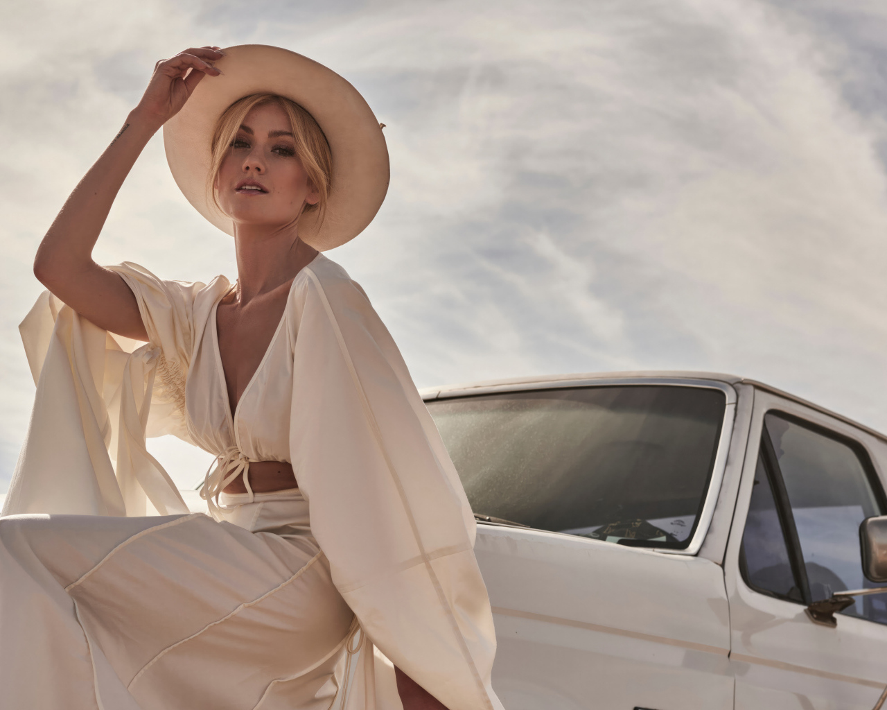 Актриса Кэтрин Макнамара в белом костюме сидит на автомобиле