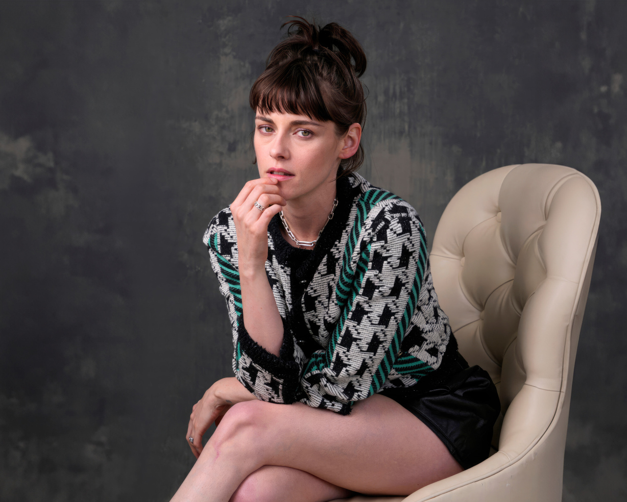 Актриса Кристен Стюарт сидит в кресле на фоне серой стены
