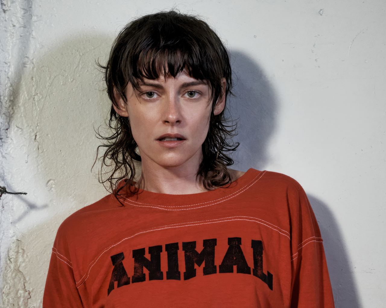 Актриса Кристен Стюарт стоит у серой стены