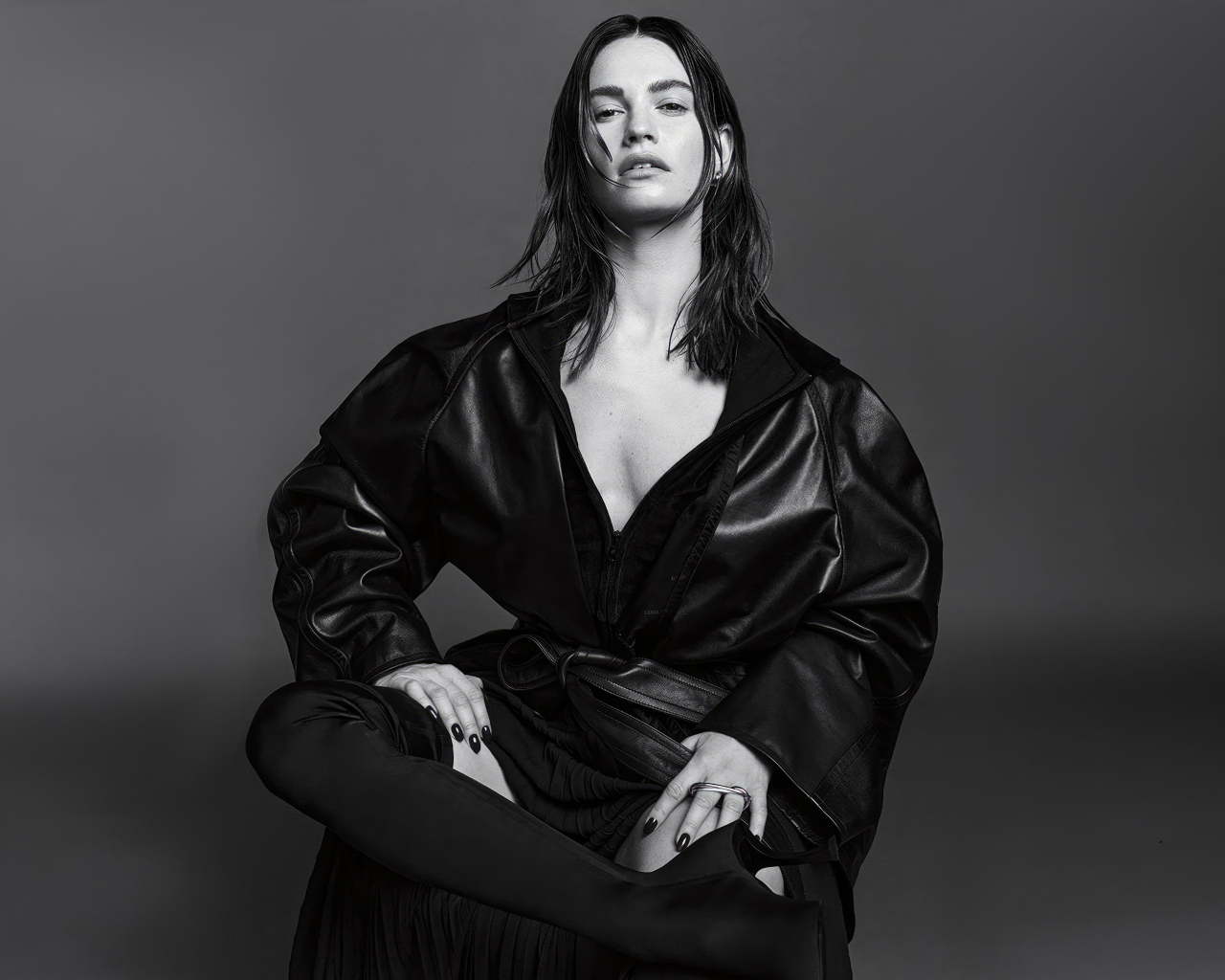 Актриса Лили Джеймс в черном наряде на сером фоне