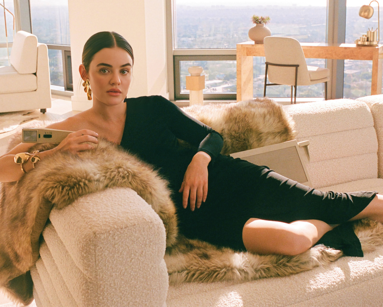 Актриса Люси Хейл в черном платье лежит на диване