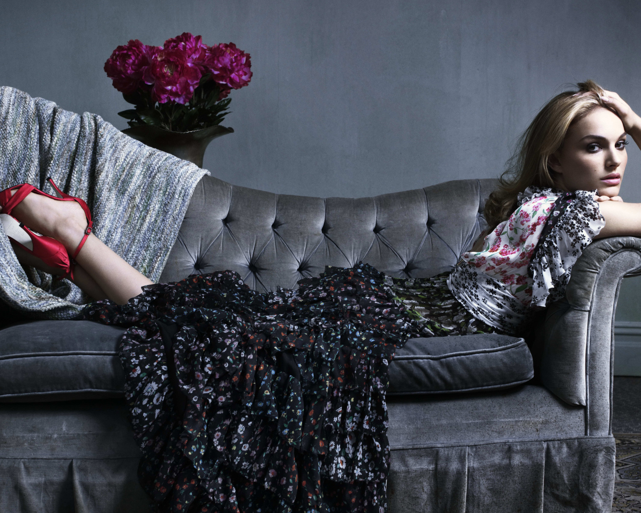 Актриса Натали Портман в платье лежит на сером диване
