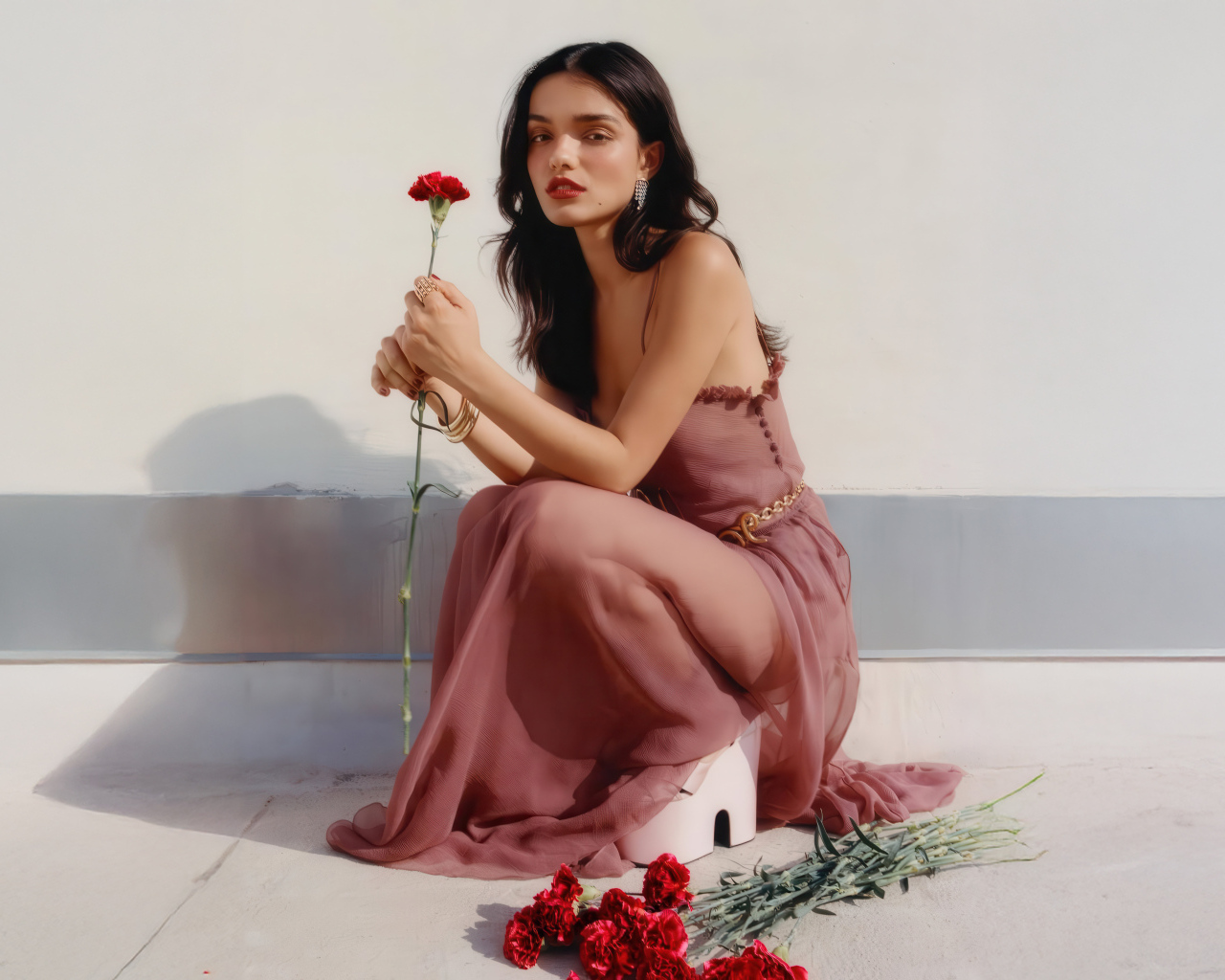 Актриса Рэйчел Зеглер с красными гвоздиками сидит на полу