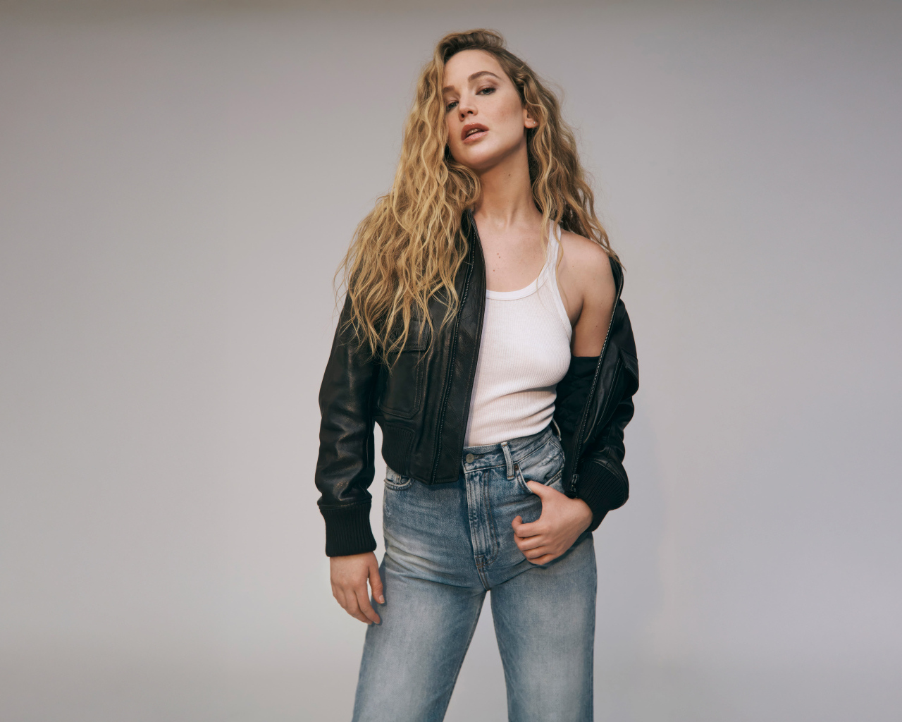 Американская актриса Дженнифер Лоуренс  в джинсах на сером фоне