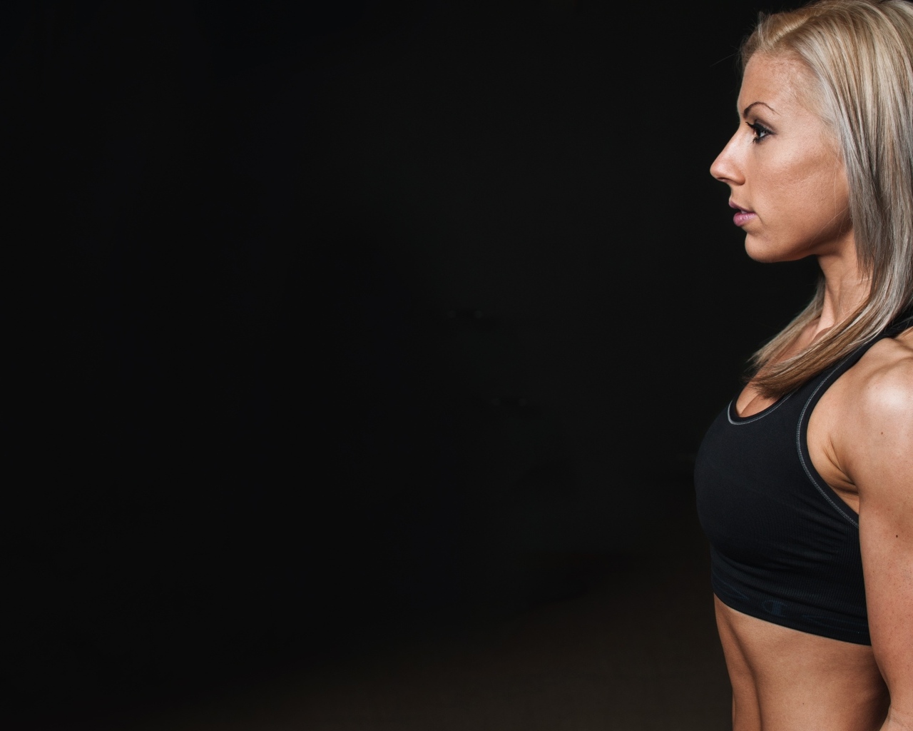 Спортивная блондинка стоит на черном фоне