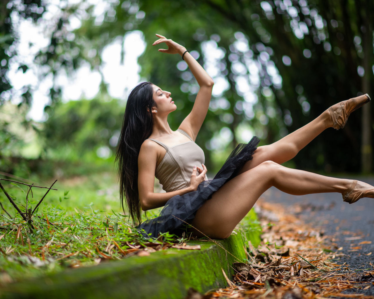 Девушка балерина в короткой юбке сидит на земле