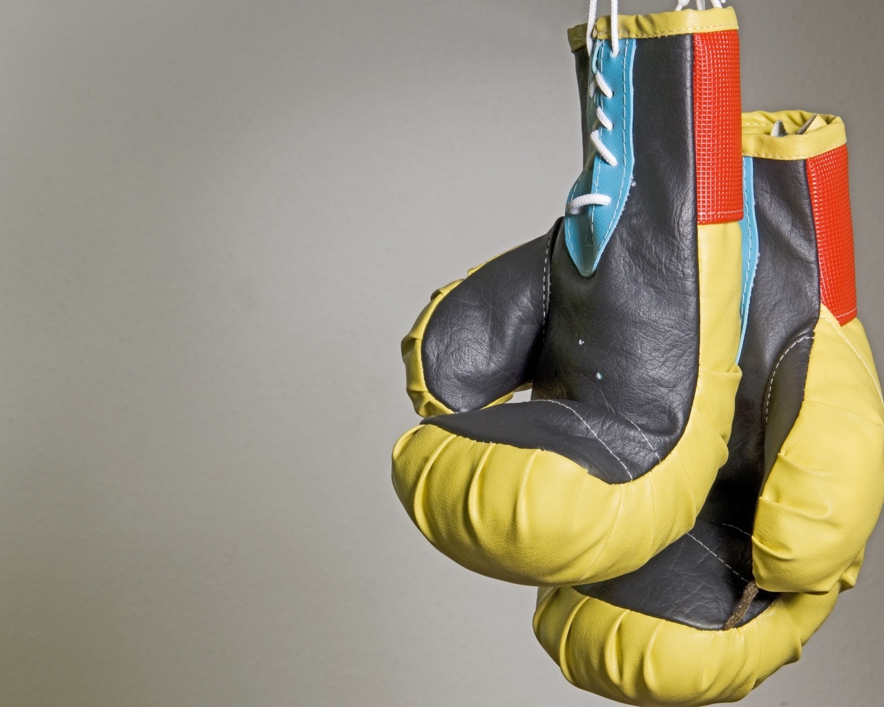 Боксерские перчатки на фоне серой стены 