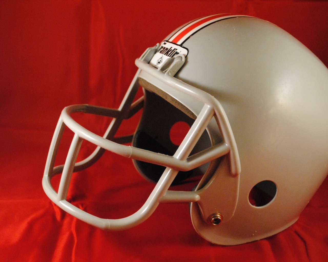 Шлем для игры в американский футбол на красном фоне