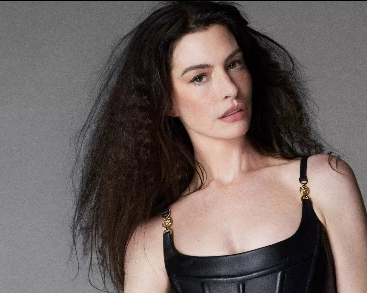 Длинноволосая актриса Энн Хэтэуэй на сером фоне