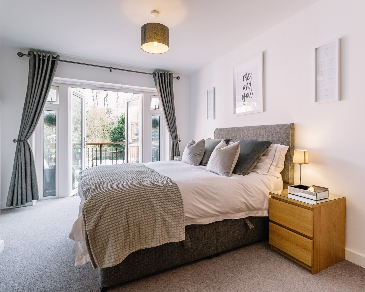 Открытое окно в спальне с большой серой кроватью