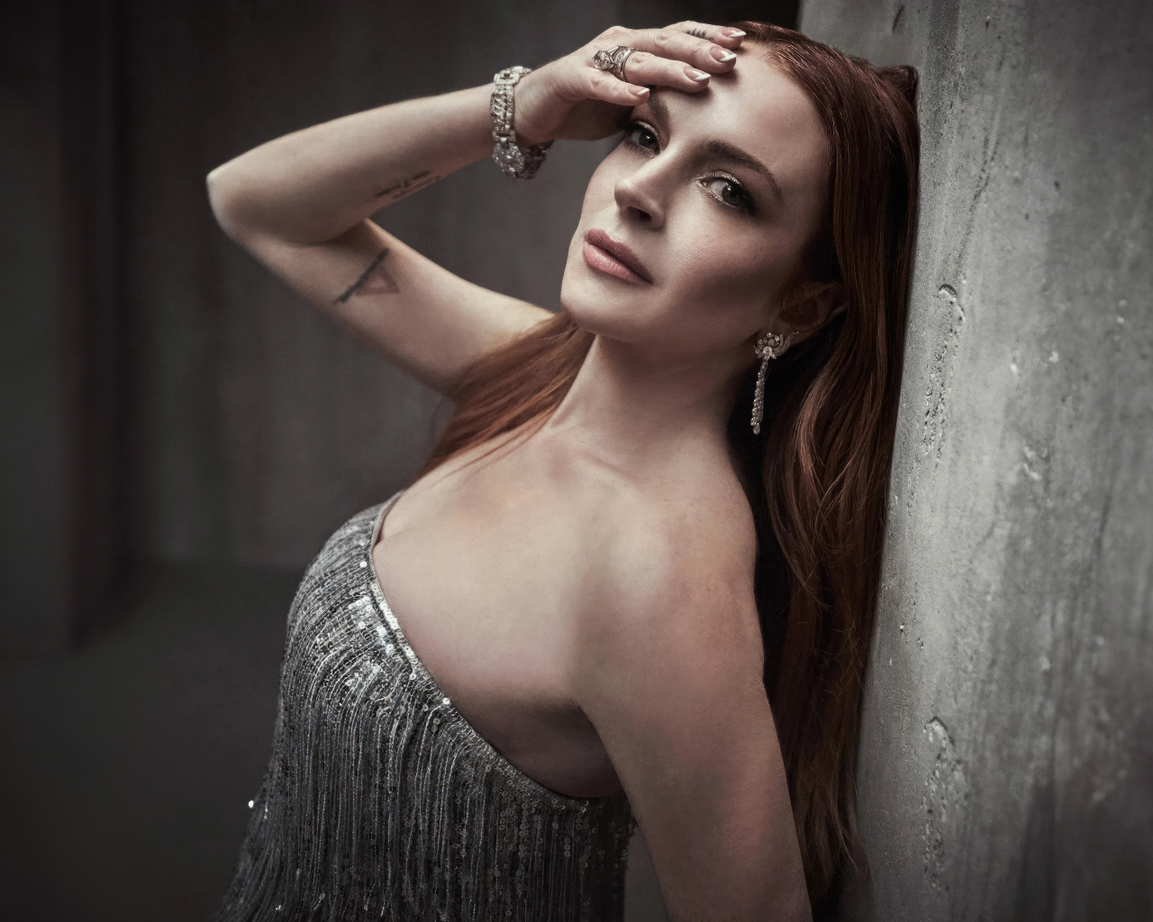 Рыжеволосая актриса Линдси Лохан стоит у стены